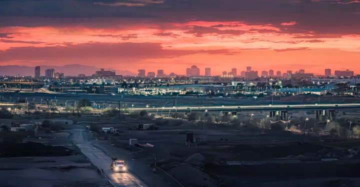 A city skyline beneath a glowing orange evening sky