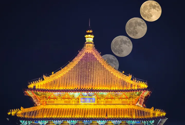 A sequence of moons above an illuminated traditional roof