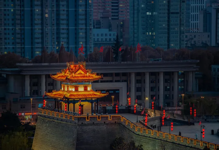 An illuminated traditional tower framed by modern buildings